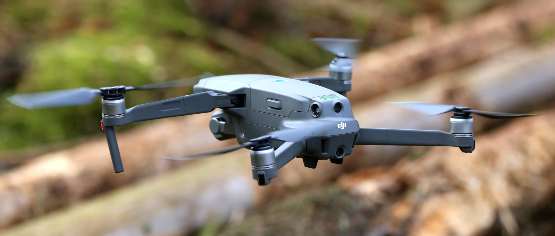 Eine Drohne schebt über liegenden Baumstämmen.