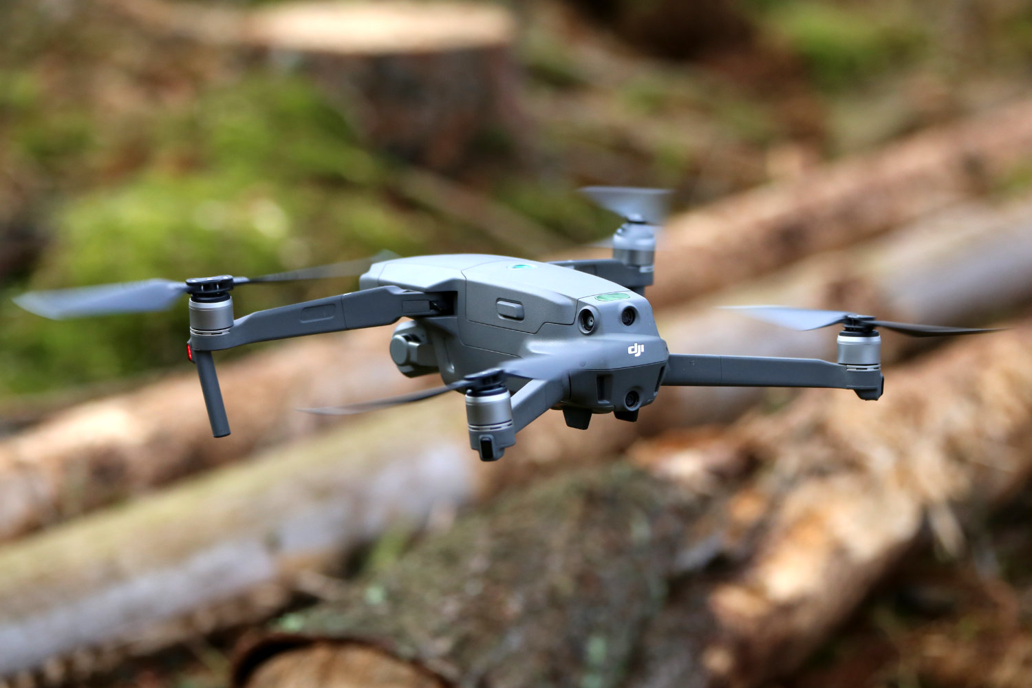 Eine Drohne schebt über liegenden Baumstämmen.