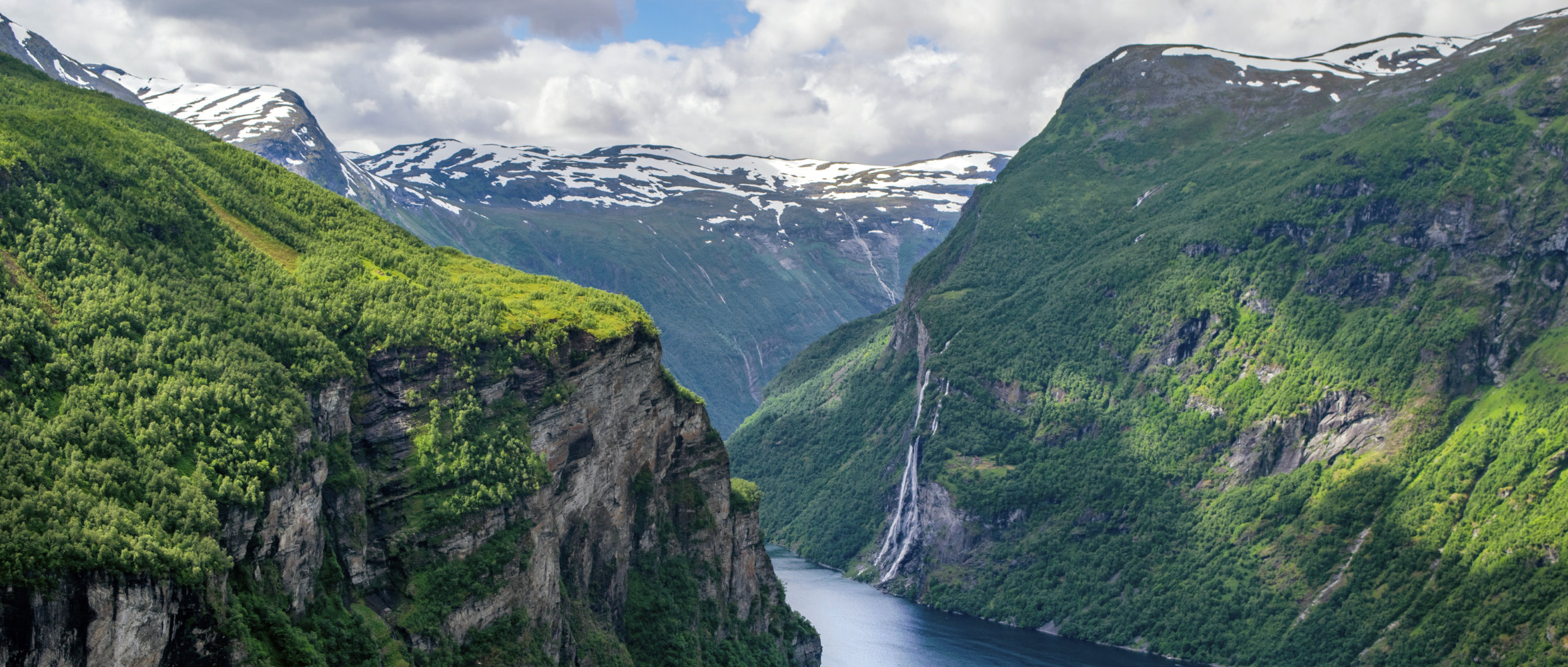 Ein Fjord mit bewaldten Hängen in Norwegen.